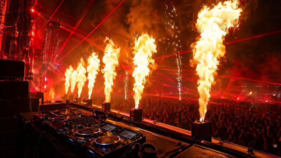 Scena festiwalu w ogniu: płomienie z armatek, czerwone lasery i stanowisko DJ-a